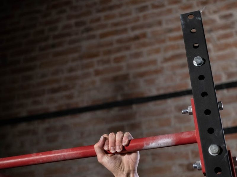 Close-up of a man's hands gripping a pull-up bar.