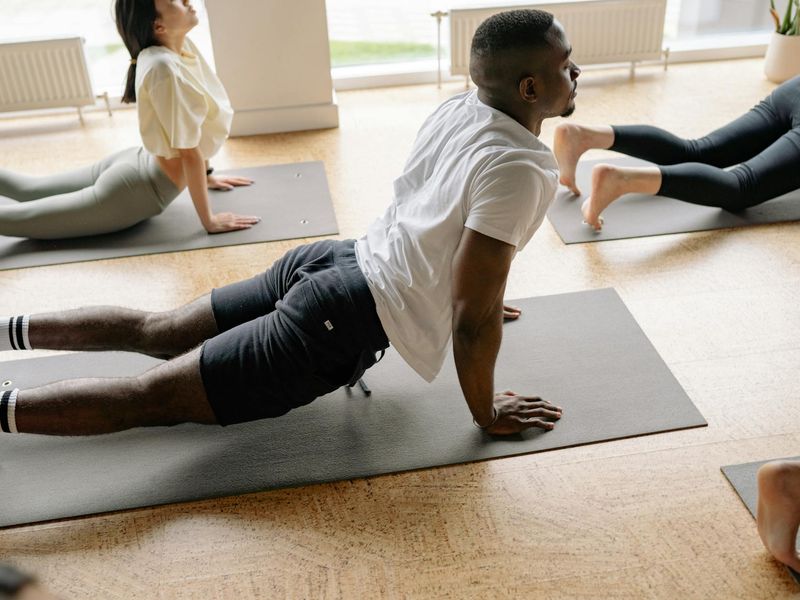 Man stretching on a yoga mat in a well-lit room.